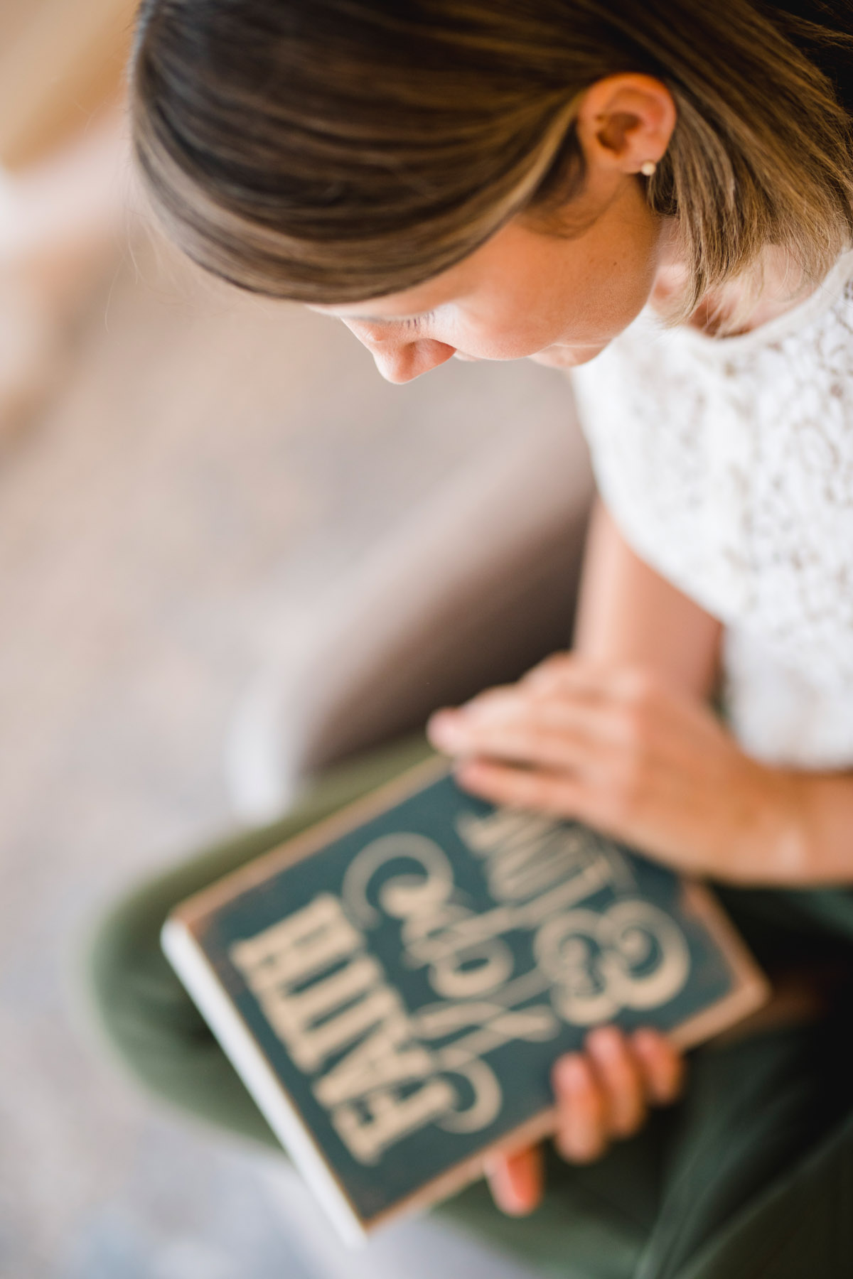 Frau sitzt in einem Sessel und schlägt ein Buch auf