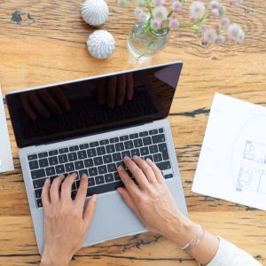 Person schreibt auf einem Laptop am Tisch