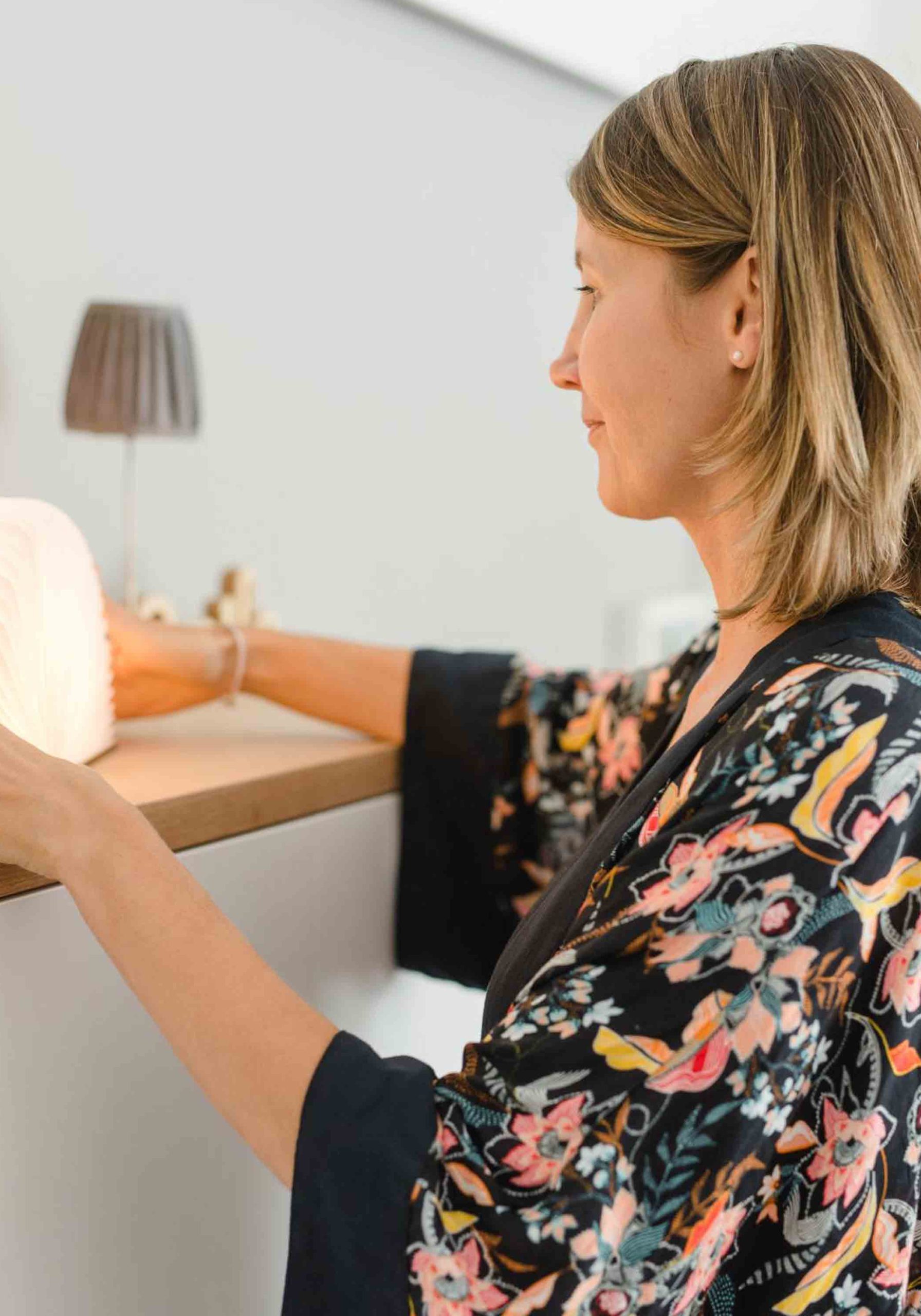 Frau in schwarzem Kimono dekoriert ein Sideboard